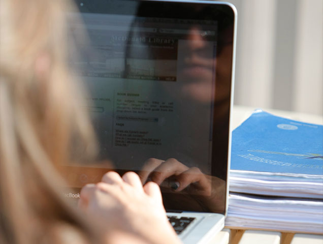 Student looking into laptop screen while working on design