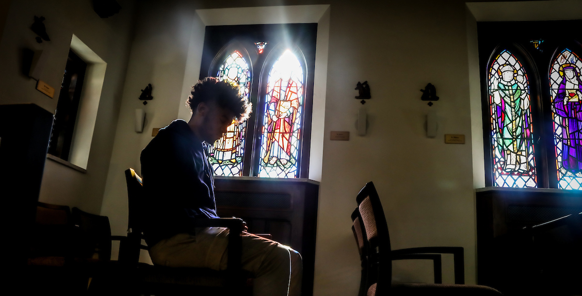 student praying in chapel