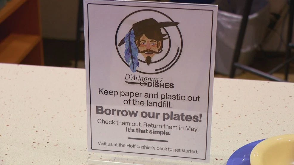 Sign on dining commons table that reads: D'Artagnan's dishes. Keep paper and plastic out of the landfill. Borrow our plates! Check them out. Return them in May. It's that simple!