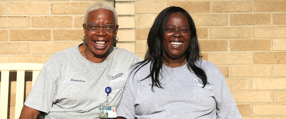 Two Xavier employees sitting on a bench smiling with each other