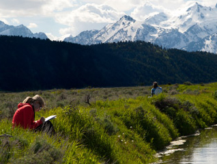 Students writing near a stream during an immersion trip in the wilderness
