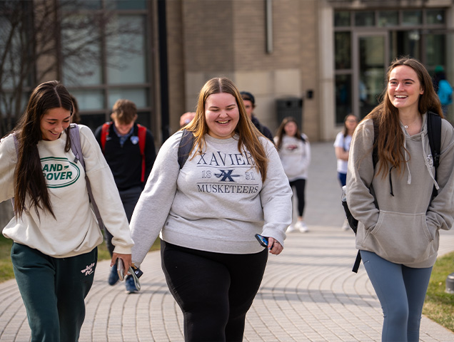 Three students walking smiling and laughing on campus