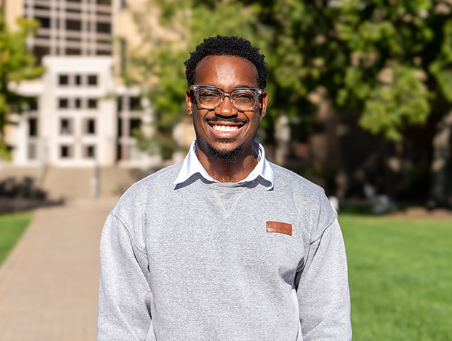 Xavier student smiling on campus wearing a grey Xavier sweatshirt