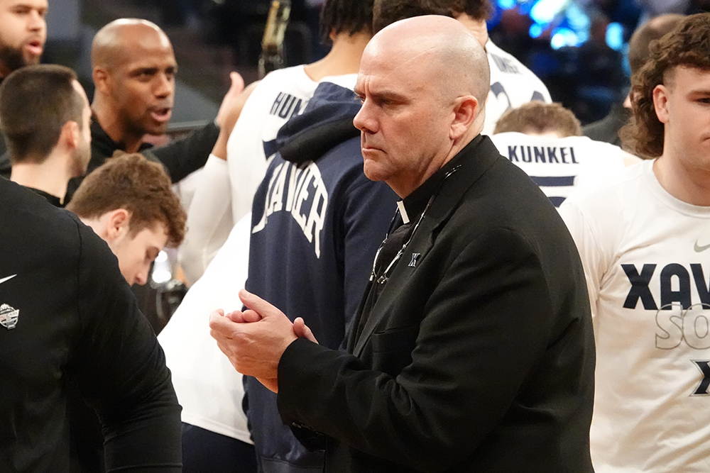 Father Bill Murphy stands with the Xavier Musketeers men's basketball team at Madison Square Garden in New York City.