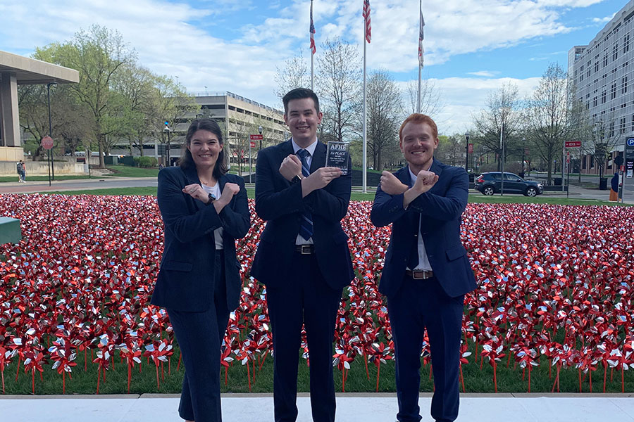 Xavier Master of Health Services Administration students Brittany Schaulis, Steven Kunz and Cayden Owens make an X symbol with their hands on the campus of The Ohio State University.