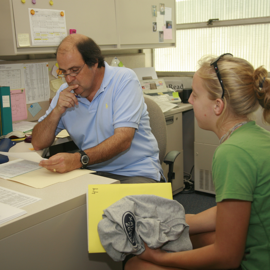 Paul Colella works with a student and looks at their paper during office hours