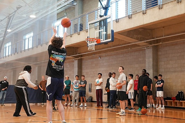 a student shoots a basketball from the three point line on the basketball court in the Health United Building