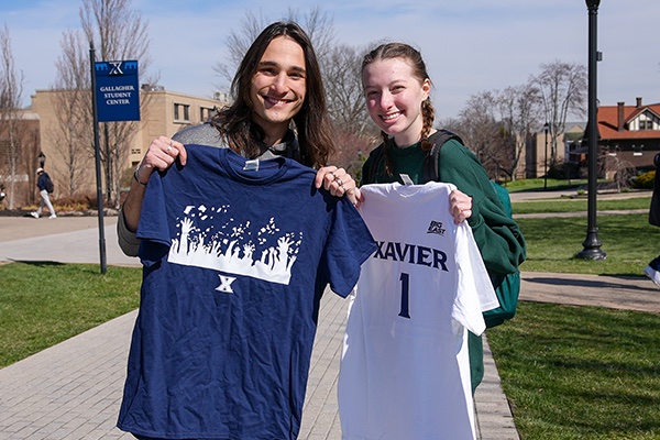 Two students smile with their Xavier t-shirts