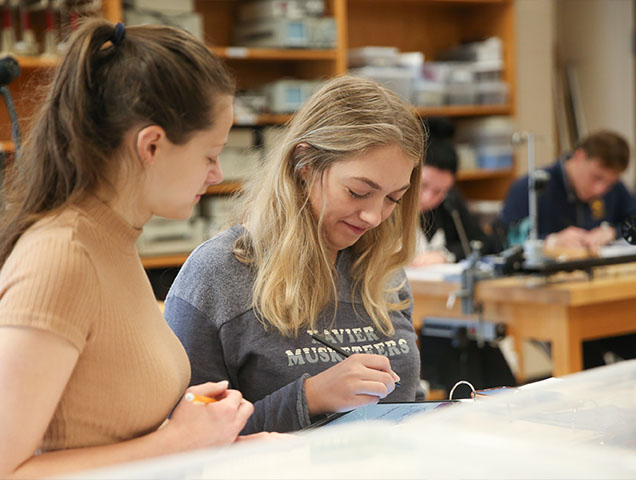 Two Xavier students working together in a classroom on a project