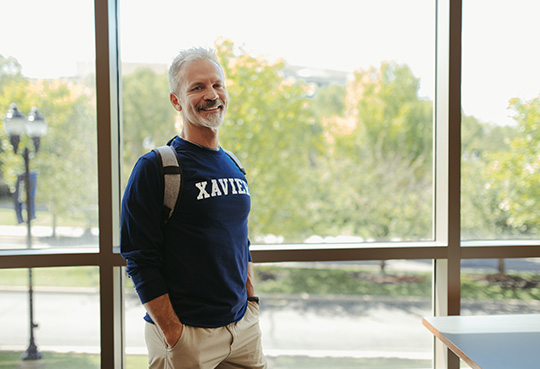 Xavier APEX student standing in front of windows 