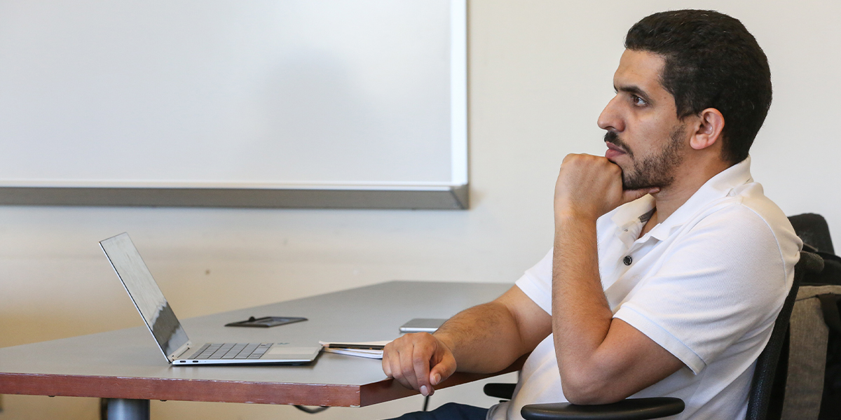 Graduate student sitting at desk in a classroom with laptop open